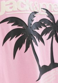 Tissu rose avec des motifs en relief de palmiers noirs et un texte blanc "jack&j" partiellement visible en haut.