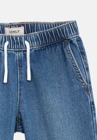 Calções de ganga azul com cintura elástica, cordão branco, bolsos laterais e uma pequena etiqueta da marca na cintura.