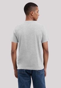 Grijze katoenen T-shirt met korte mouwen, een ronde hals en een zachte textuur. Model wordt van achteren getoond, draagt blauwe jeans.