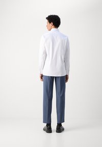 Biała koszula z guzikami, niebieskie spodnie i czarne buty. Prosty design, gładki materiał, regularny krój koszuli, jednolity wzór.