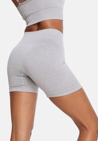 Sive visoko pasne aktivne kratke hlače iz elastičnega materiala, z oprijetim krojem in gladko teksturo, ki se končajo malo nad kolenom.