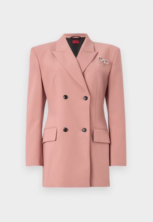 Blazer croisé en tissu rose doux, doté d'un col à revers, de deux poches avant, de boutons noirs et d'une broche en forme de nœud argenté.