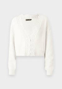 Weiße, kurze Strickjacke, weicher Stoff, gewellter Spitzenbesatz entlang des Ausschnitts, vier kleine Knöpfe, lange Ärmel.
