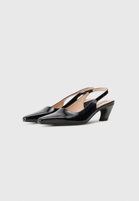 Talons slingback en cuir verni noir avec un embout pointu, un petit talon et un design de côté découpé. Texture lisse et style minimaliste.