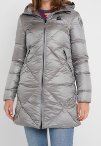 Grijze pufferjas met een ruitvormig quiltpatroon, voorrits, twee zijvakken, afneembare capuchon en een zachte glansafwerking.