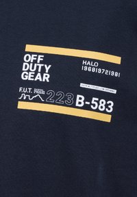 Navyblauwe T-shirt met witte en gele tekst, waaronder "OFF DUTY GEAR" en "HIGH ALTITUDE LOW OPENING" met verschillende numerieke codes.