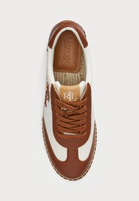 Viazačkové tenisky s krémovým plátnom a hnedými koženými akcentmi. Majú okrúhlu špičku, okrúhle šnúrky a šitú gumovú podrážku.