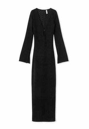 Juodas ilgas rankovės suknelė su V formos iškirpte, tekstūruotas audinys ir užtrauktukas nugaros pusėje. Su šoninėmis skeltuvėmis rankovėse, kad būtų patogiau judėti.