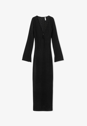 Juodas ilgas rankovės suknelė su V formos iškirpte, tekstūruotas audinys ir užtrauktukas nugaros pusėje. Su šoninėmis skeltuvėmis rankovėse, kad būtų patogiau judėti.