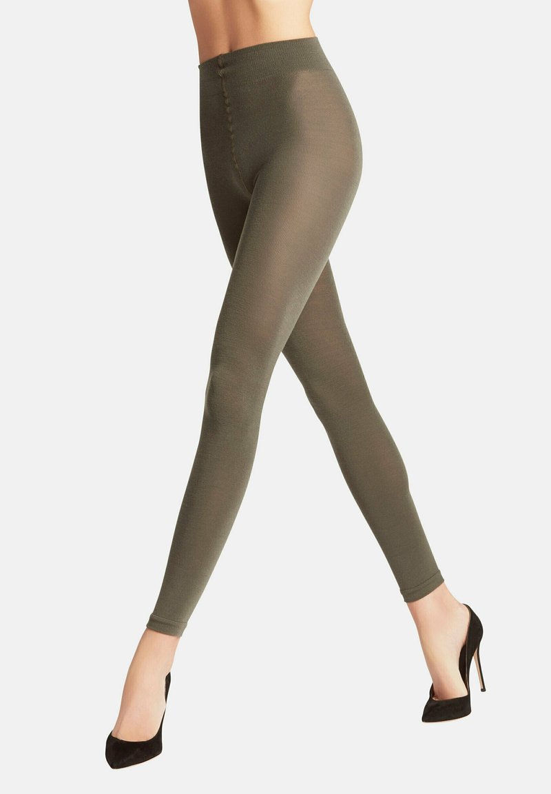 Olijfgroene leggings met een soepele textuur, hoge tailleband en nauwsluitend ontwerp, gecombineerd met zwarte hoge hakken.