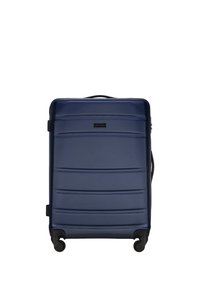 Valigia rigida navy con superficie testurizzata, scanalature orizzontali, maniglia superiore, quattro ruote e una maniglia laterale per un facile trasporto.