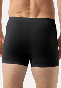 Czarne bokserki w stylu trunk z fakturowanej tkaniny, z gładkim paskiem w talii i dopasowanym krojem sięgającym do połowy uda.