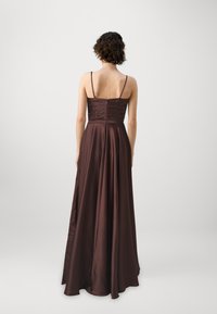 Καφέ σατέν βραδινό φόρεμα με ρυθμιζόμενες λεπτές τιράντες, εφαρμοστό κορσέ και ροή στο κάτω μέρος. Διαθέτει κλείσιμο με φερμουάρ και πτυχώσεις στο πίσω μέρος.