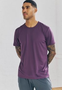 Paarse sport t-shirt van een textuur, ademende stof. Korte mouwen en een ronde halslijn. Grijze shorts met een subtiele logo-detail.