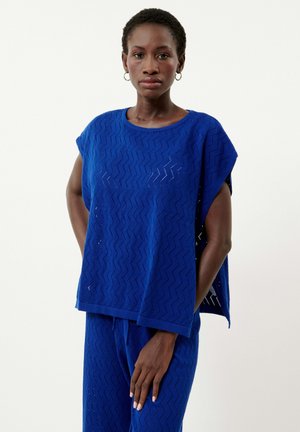 Haut en maille texturée bleue avec motif en zigzag, coupe ample, manches larges et col rond, associé à un bas bleu assorti.