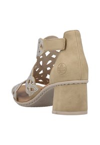 Sandale à talon haut beige en suède texturé, avec un design découpé, ornée de rhinestones et dotée d'un solide talon épais.