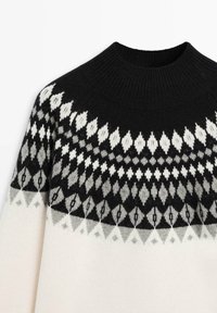 Pull tricoté noir, blanc et gris avec un col rond haut et un motif en losange sur la poitrine et les épaules.