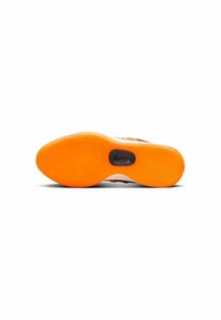 Shoe sole with an orange rubber bottom featuring textured wave patterns and a circular black logo at the center. White side accents visible.