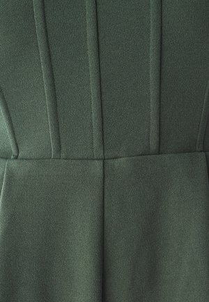 Tejido verde texturizado con detalles de costura vertical, superficie suave y diseño ajustado. Sin hardware ni patrones visibles.