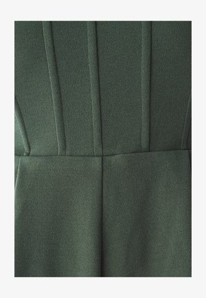 Tessuto verde con texture, dettagli di cuciture verticali, superficie liscia e design su misura. Nessun hardware o modello visibile.