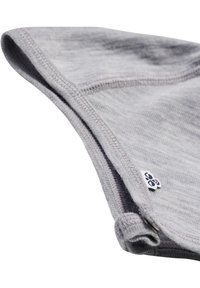 Szary materiał tekstylny, miękka struktura, ukośny widok ukazujący szczegóły szwów. Mała metka z widocznym logo. Lekka, elastyczna konstrukcja.