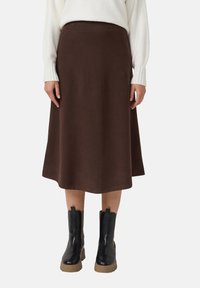 Bruine midilengte rok van zachte stof met een wijde, uitlopende pasvorm. Gecombineerd met zwarte enkellaarsjes met een gestructureerd ontwerp.