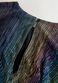 Abito plissettato realizzato in un tessuto metallico multicolore con linee ondulate. Chiusura sul retro con un bottone nero. Texture liscia e brillantezza vivace.