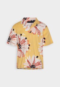 Korte mouwen shirt van gele katoen met grote bloemmotieven in roze en zwart, met een knoopsluiting aan de voorkant en een klassieke kraag.