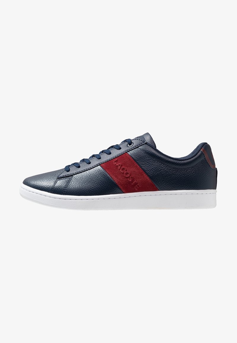 Baskets en cuir marine avec une bande rouge d'accent, semelle en caoutchouc blanc et lacets bleus. Caractéristiques d'une surface texturée et d'un logo de marque. Design classique à tige basse.
