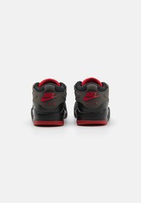 Nike sneakers med et sort og gråt design, røde detaljer, polstret krave og en struktureret sål. Branding synlig på hælen og tungen.