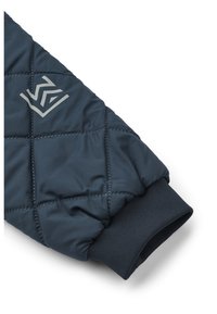 Navy blue quilted jacket sleeve with a ribbed cuff, featuring a contrasting gray logo and stitched pattern for insulation.