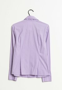 Camicia a maniche lunghe in tessuto lilla chiaro con colletto a punta. Presenta cuciture strutturate e una piega sul retro per facilitare i movimenti.