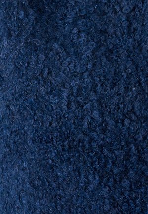 Primer plano de tejido de lana azul oscuro, rizado y apretado, con fibras visibles y bucles suaves y densos.