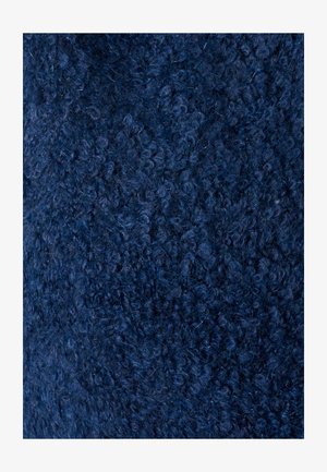 Primer plano de tejido de lana azul oscuro, rizado y apretado, con fibras visibles y bucles suaves y densos.