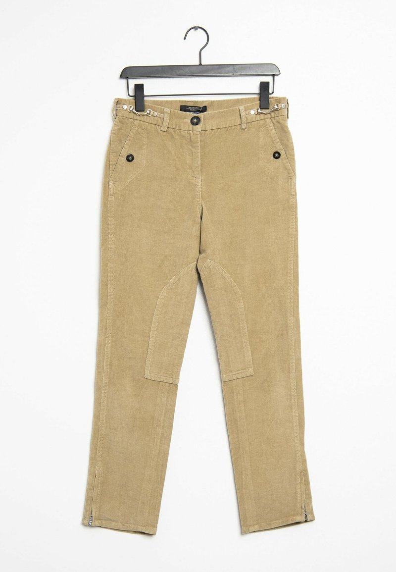 Pantalon en velours côtelé beige avec un bouton et une fermeture éclair à l'avant, poches latérales avec boutons et fermetures éclair au niveau des jambes, présenté suspendu sur un cintre noir.
