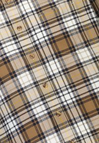 Camicia a quadri marrone e beige realizzata in cotone con chiusura a bottone, caratterizzata da modelli a scacchi variabili, sottili linee nere e accenti gialli.