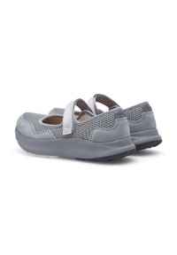 Los zapatos grises presentan una parte superior de malla y gamuza con una doble tira. El diseño de perfil bajo incluye una suela de goma texturizada para mayor agarre.