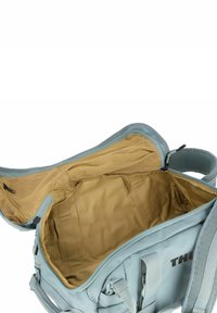 Bolsa de deporte azul claro con una apertura con cremallera, que cuenta con un interior beige, bolsillo de malla y una forma estructurada. Logo visible en el lado.