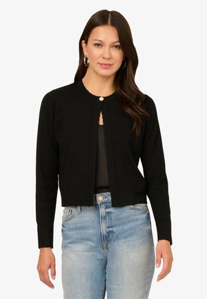 Black knitted cardigan with long sleeves, round neckline, and a single button closure. Features a cropped design and soft texture.
