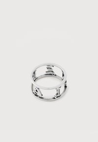 Inel metalic argintiu cu forme decupate care formează litere, aranjate în jurul circumferinței acestuia pe un fundal alb.