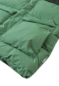 Giacca imbottita verde con molteplici tasche, una texture liscia e chiusure a scatto. Include un'etichetta del brand nell'angolo inferiore.