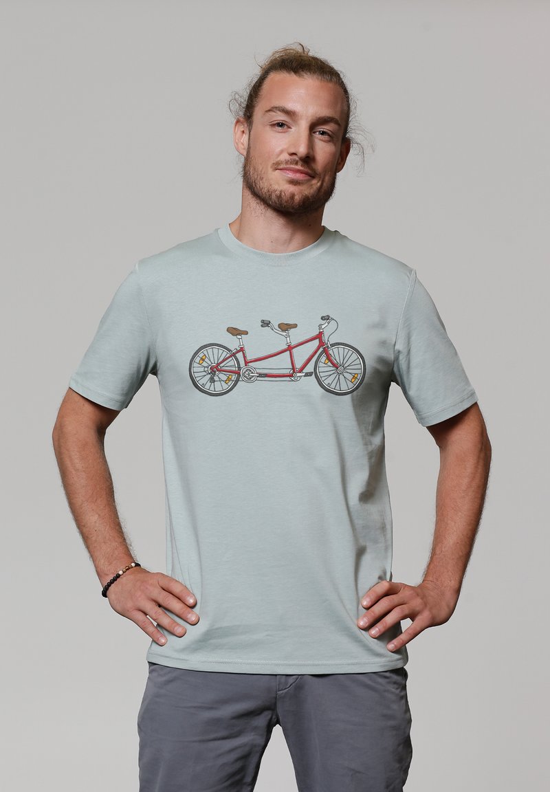 T-shirt bleu clair avec un graphique d'un vélo tandem rouge. Le design inclut des accents de siège marron et des roues noires. Texture de tissu douce.