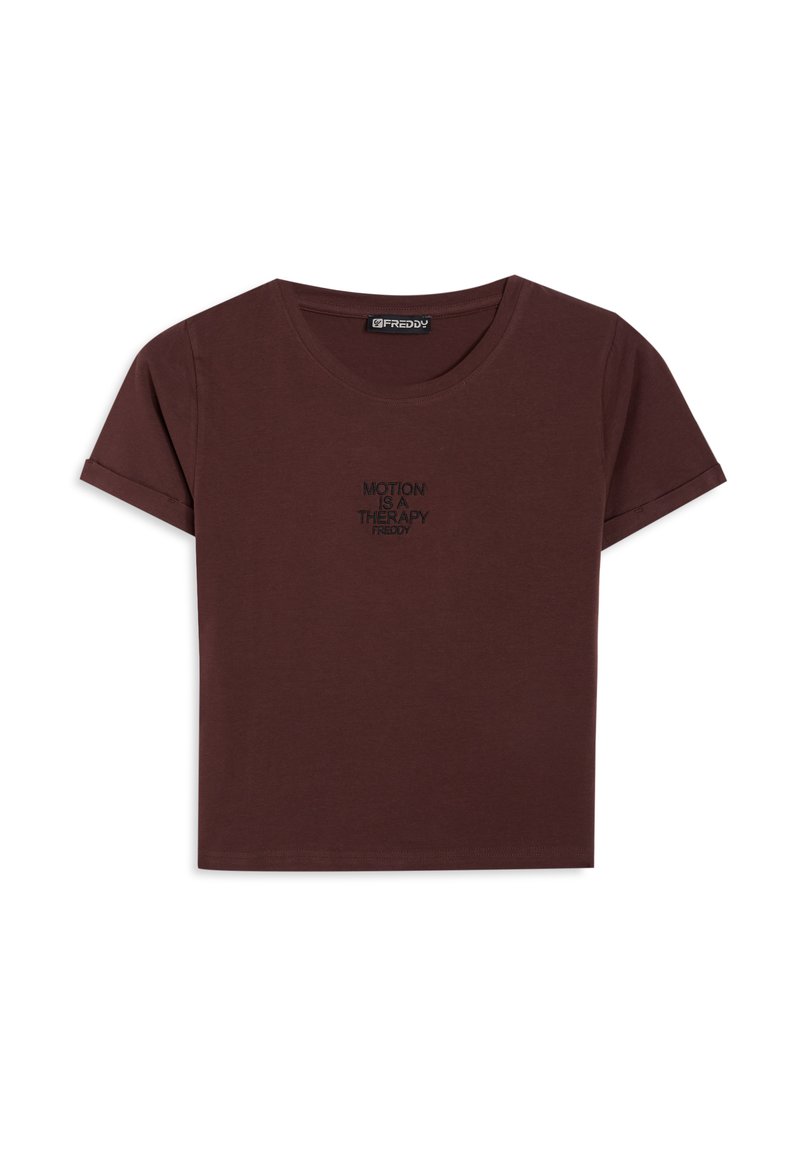 Camiseta de manga corta color burdeos, hecha de algodón, con cuello redondo y mangas remangadas; presenta un texto negro "MOTION IS A THERAPY" en la parte frontal.