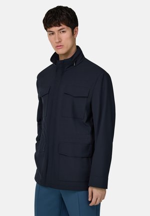 Marineblaue Jacke mit Stehkragen, ausgestattet mit vier Vordertaschen, schlankem Design und glatter Textur. Maßgeschneiderte Passform, funktional und modern.