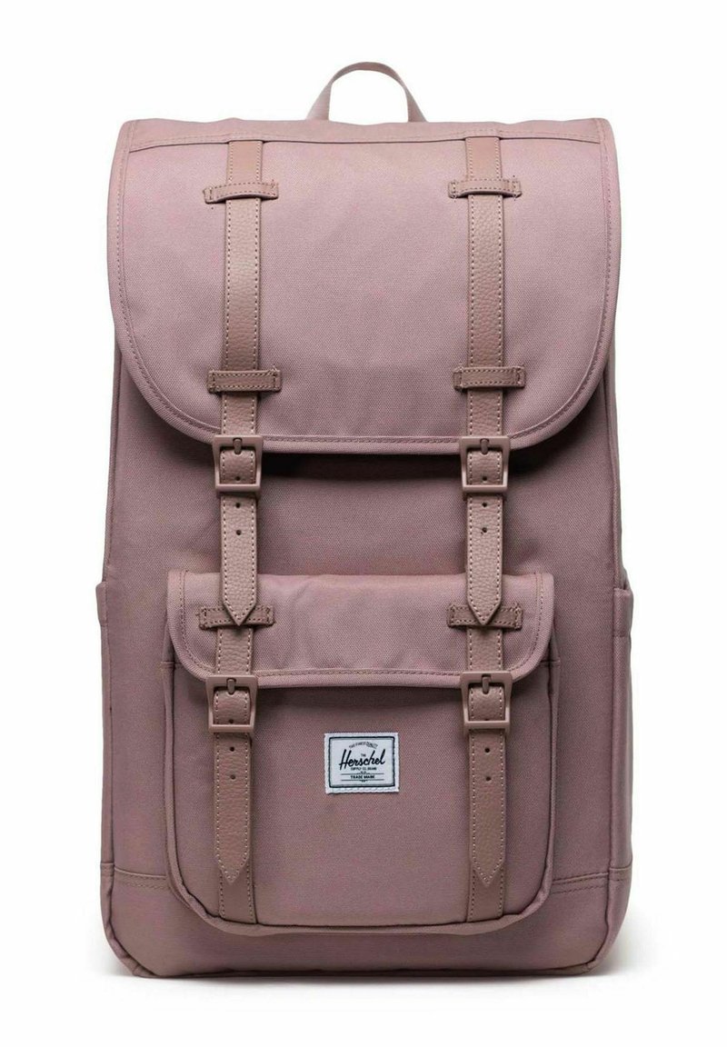 Sac à dos mauve avec des sangles de boucle à l'avant, fermeture à rabat, poche avant avec boucles et étiquette de marque Herschel sur la poche.