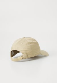 Khaki baseballkeps med rundad krona och böjd skärm, tillverkad av mjukt tyg, med justerbar rem och subtil logotypdetalj.