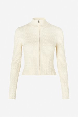 Krémově zbarvený krátký kardigan s vysokým límcem, vybavený plným předním zipem a texturovaným vzorem copánkového pletení. Dlouhé přiléhavé rukávy.