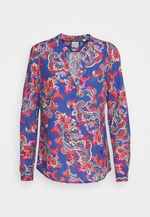 Blouse à manches longues avec base bleue et motifs floraux paisley rouges, roses et violets vifs, dotée d’un col en V subtil et de détails à boutons.
