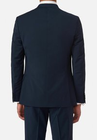 Marinblå kavaj med skräddarsydd passform, strukturerade axlar och en slät bakdel med en enda slits. Har subtil textur och knappar vid ärmsluten.