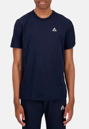 Camiseta de algodón de color azul marino, de manga corta, con cuello redondo, que presenta un pequeño logo en la zona del pecho izquierdo. Textura suave, corte casual.